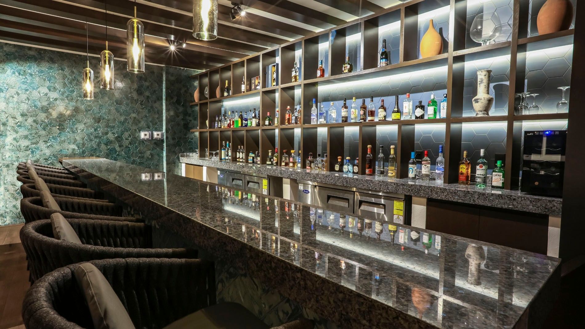 Blue Bar featuring a sleek granite counter, ambient lighting, and stocked shelves at Camino Real Veracruz