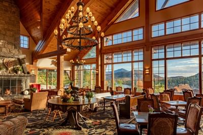 The warm timber-clad lobby of the Lake Placid Club Grandview features a stone fireplace and huge windows