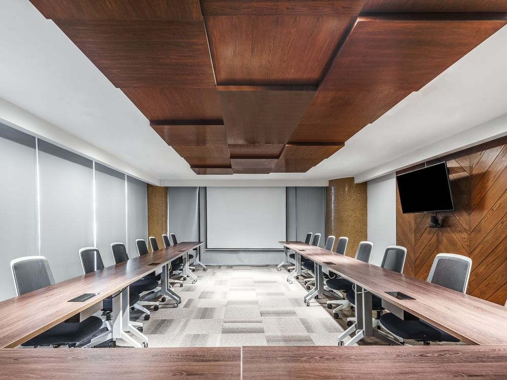 Modern boardroom Business Center 1 with wood ceiling panels and a large projection screen at Sunvivia Mazatlán