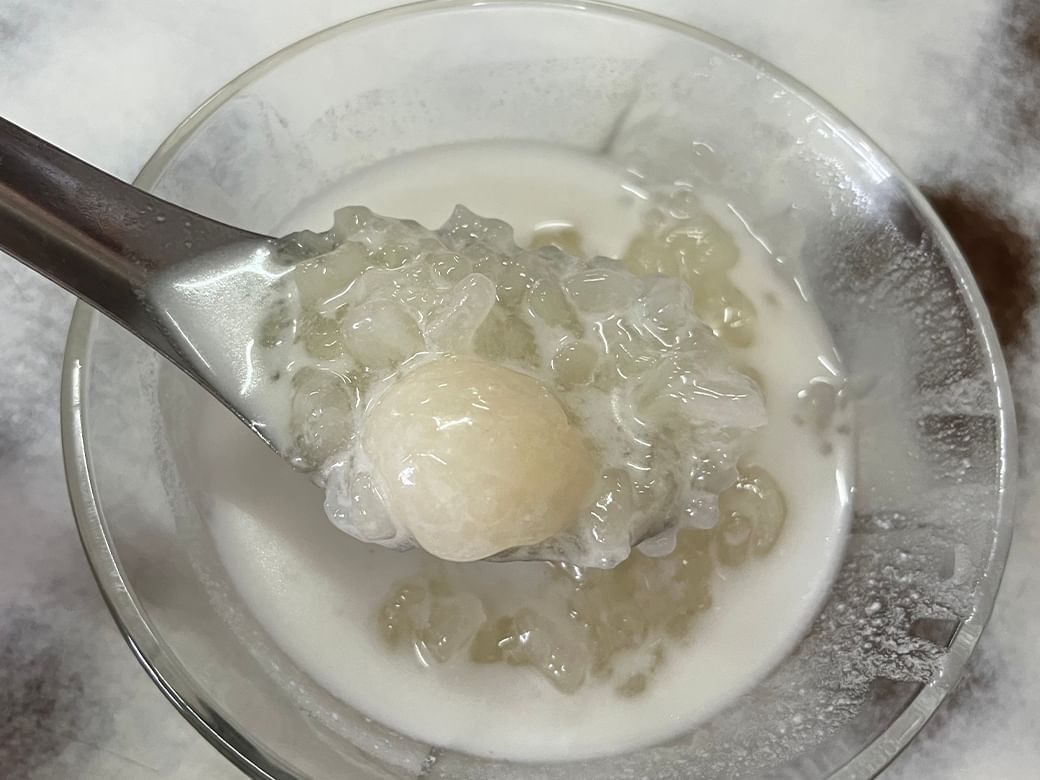Bowl of coconut milk dessert with chewy tapioca pearls and longan served chilled as a refreshing sweet near Hop Inn Hotel
