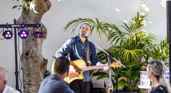 A man singing and playing a guitar at a special occasion at Encore by Mingara