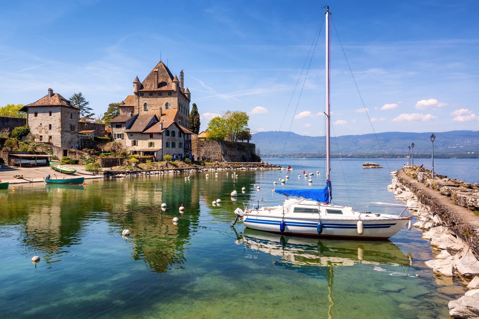 White sailboat by a stone pier near a medieval castle under a clear blue sky near Warwick Geneva