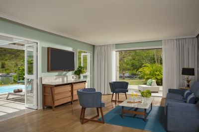 Salon avec télévision et fauteuils en peluche dans la suite présidentielle à deux chambres de Saint-Martin Beach Resort & Spa.