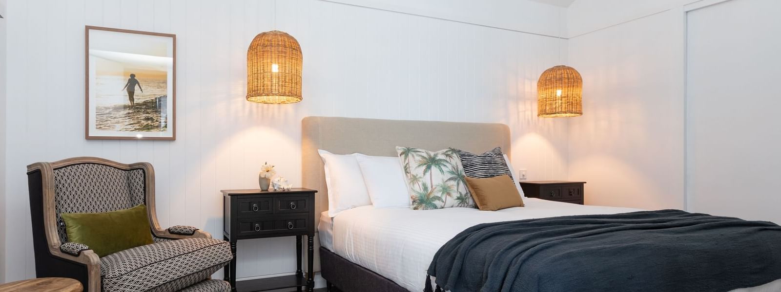 Bed by couch with carpet floors in the Grand Overwater Bungalow at Novotel Sunshine Coast Resort