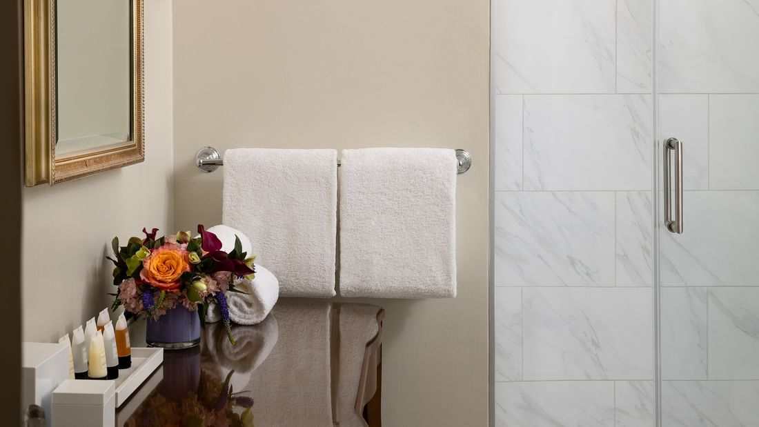 White towels on a silver rack by a marble shower wall in Deluxe Suite Accessible at Warwick Melrose Dallas