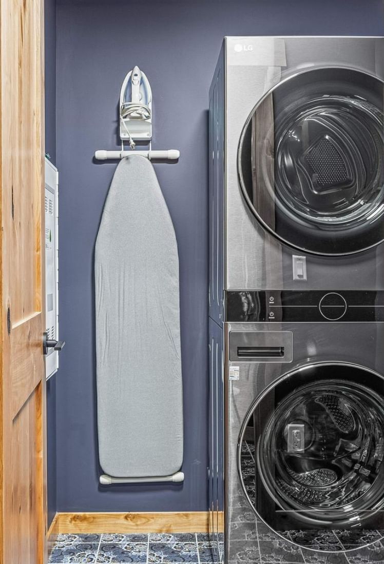 Modern laundry room with stacked washer and dryer next to an ironing board at Spring Creek Vacations