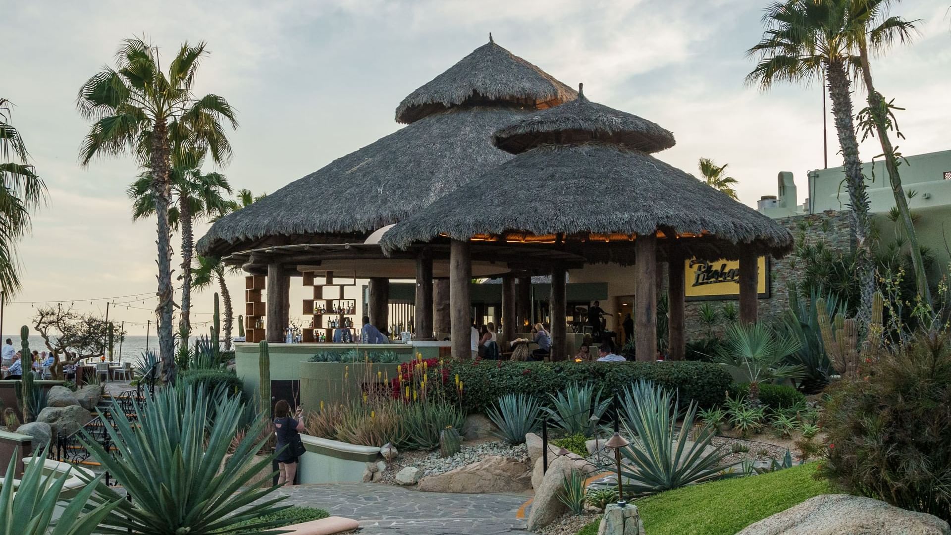 Comensales en un gran restaurante Pitahayas al aire libre, estilo palapa, con techo de paja en Hacienda del Mar Los Cabos