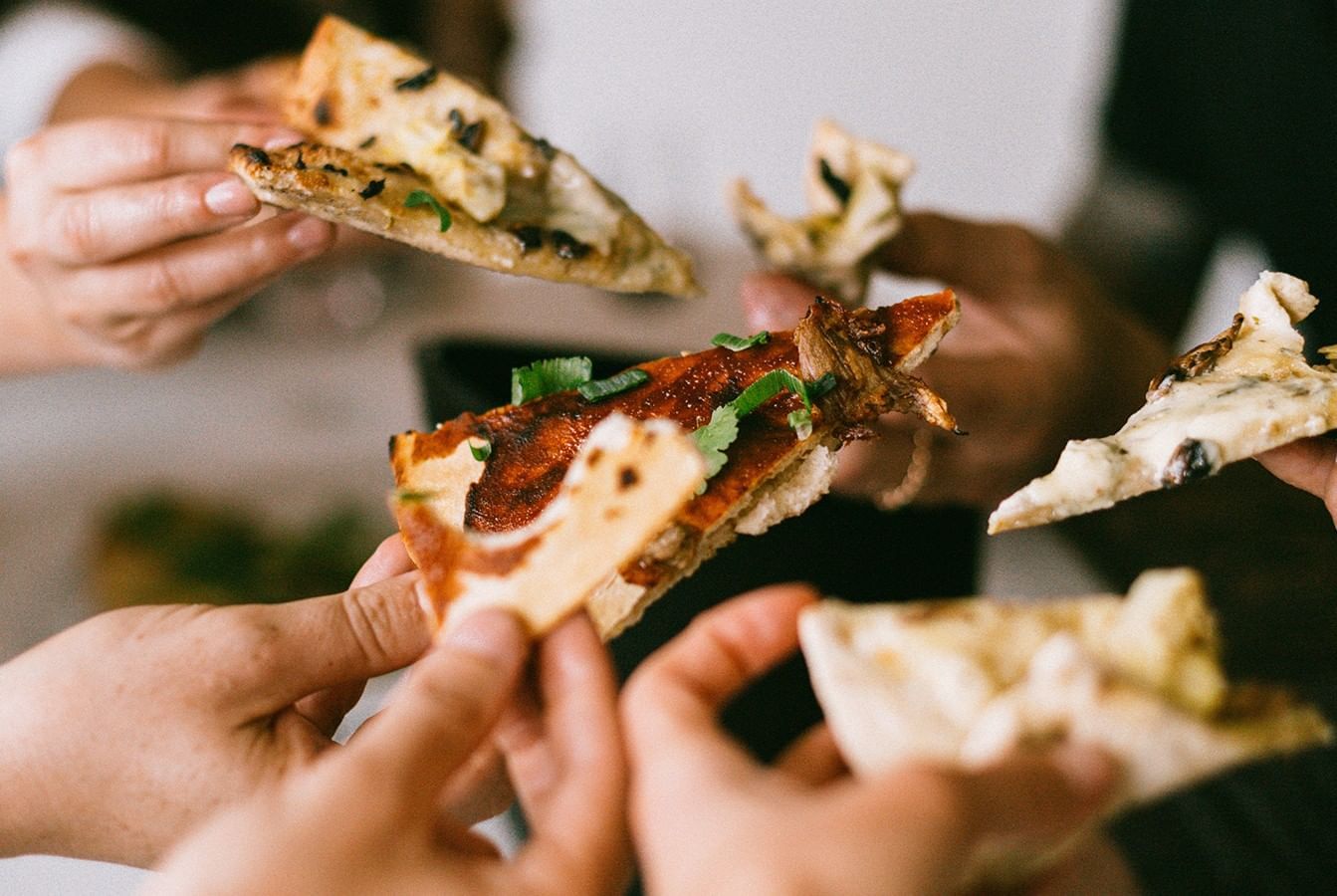 Hands holding pizza slices