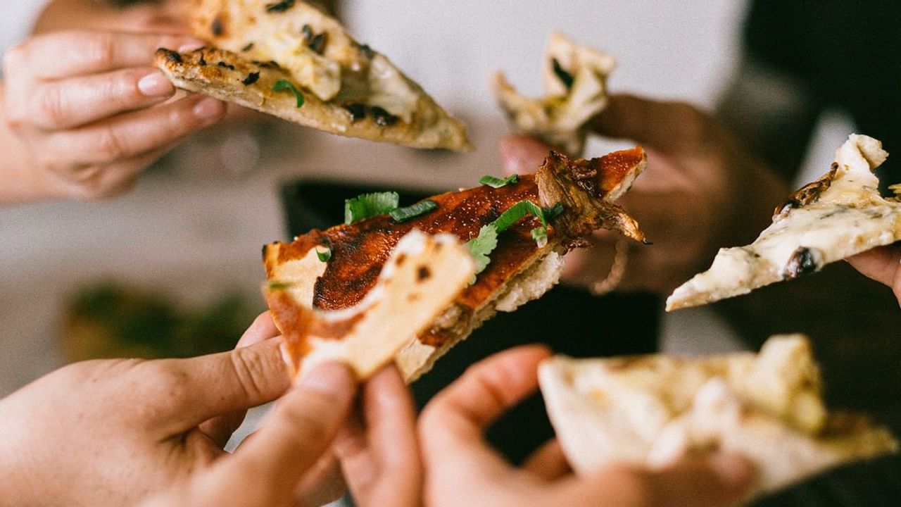 Hands holding slices of pizza