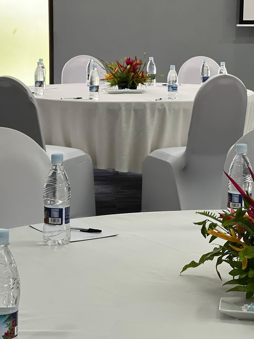 White round table by chairs with floral centerpieces in Marquee Meeting Room at Warwick Le Lagon Port villa