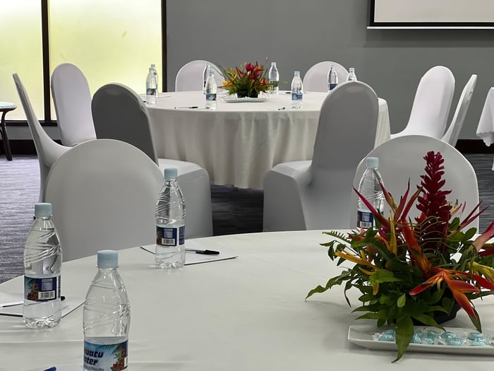 White round table by chairs with floral centerpieces in Marquee Meeting Room at Warwick Le Lagon Port villa