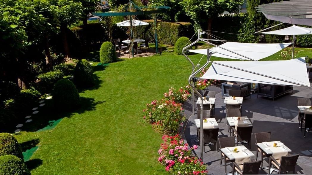 Outdoor patio of Le Lounge Restaurant with wicker chairs and tables, shaded by modern awnings at Warwick Reine Astrid - Lyon