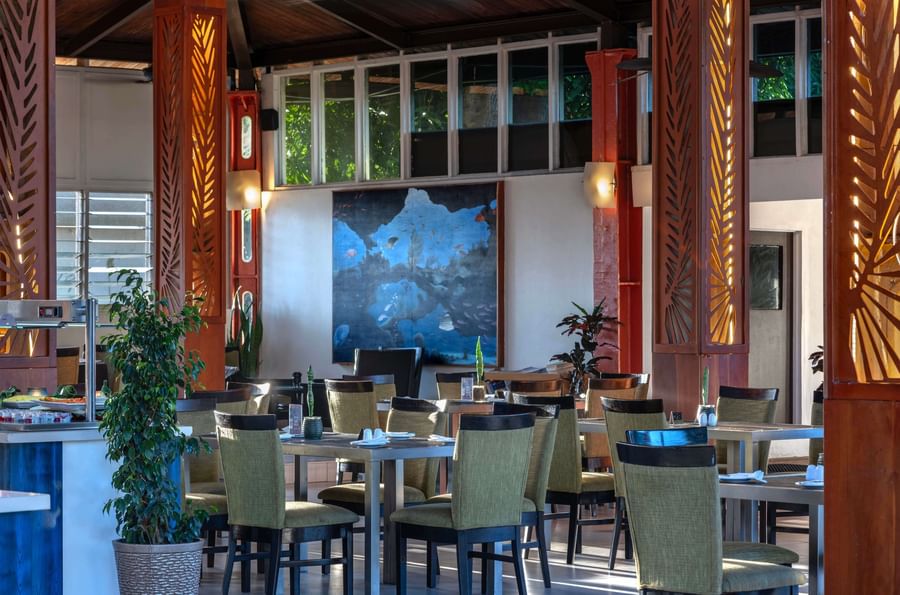 Empty dining area with tables, chairs, and artwork at Tokatoka Resort - Fiji International Airport.