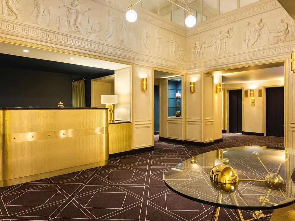 Golden reception desk and bas-relief wall art in the lobby at Hotel Barsey by Warwick