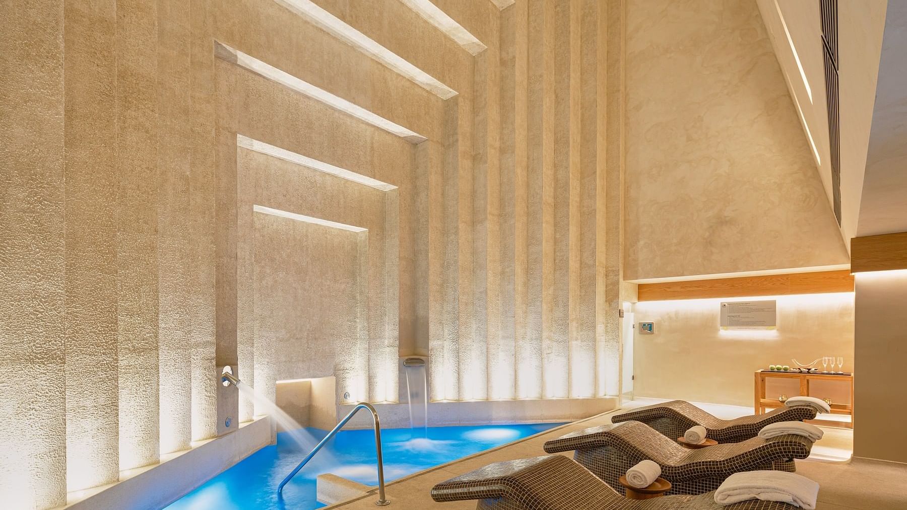 Indoor pool area with lounge chairs in the Spa Room at Grand Fiesta Americana