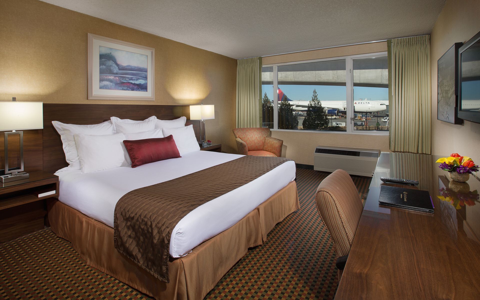 Bed and desk in hotel room with view of airport