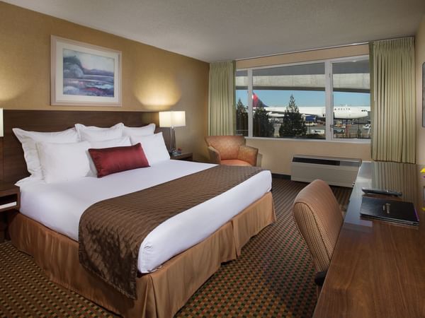 Bed and desk in hotel room with view of airport