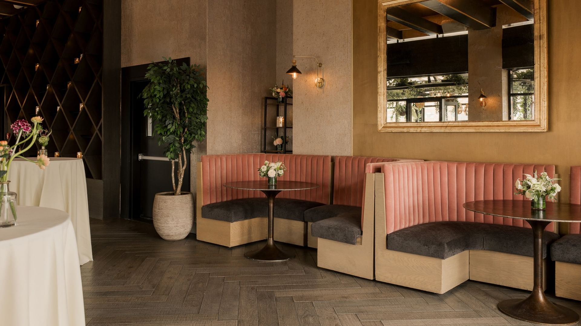 The Loft features pink banquette seating, dark wood floors, and elegant floral arrangements at Gansevoort Meatpacking NYC.