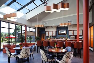 Modern hotel bar and lounge with skylights, and seating overlooking outdoor patio at Aramark Chauncey Conference Center