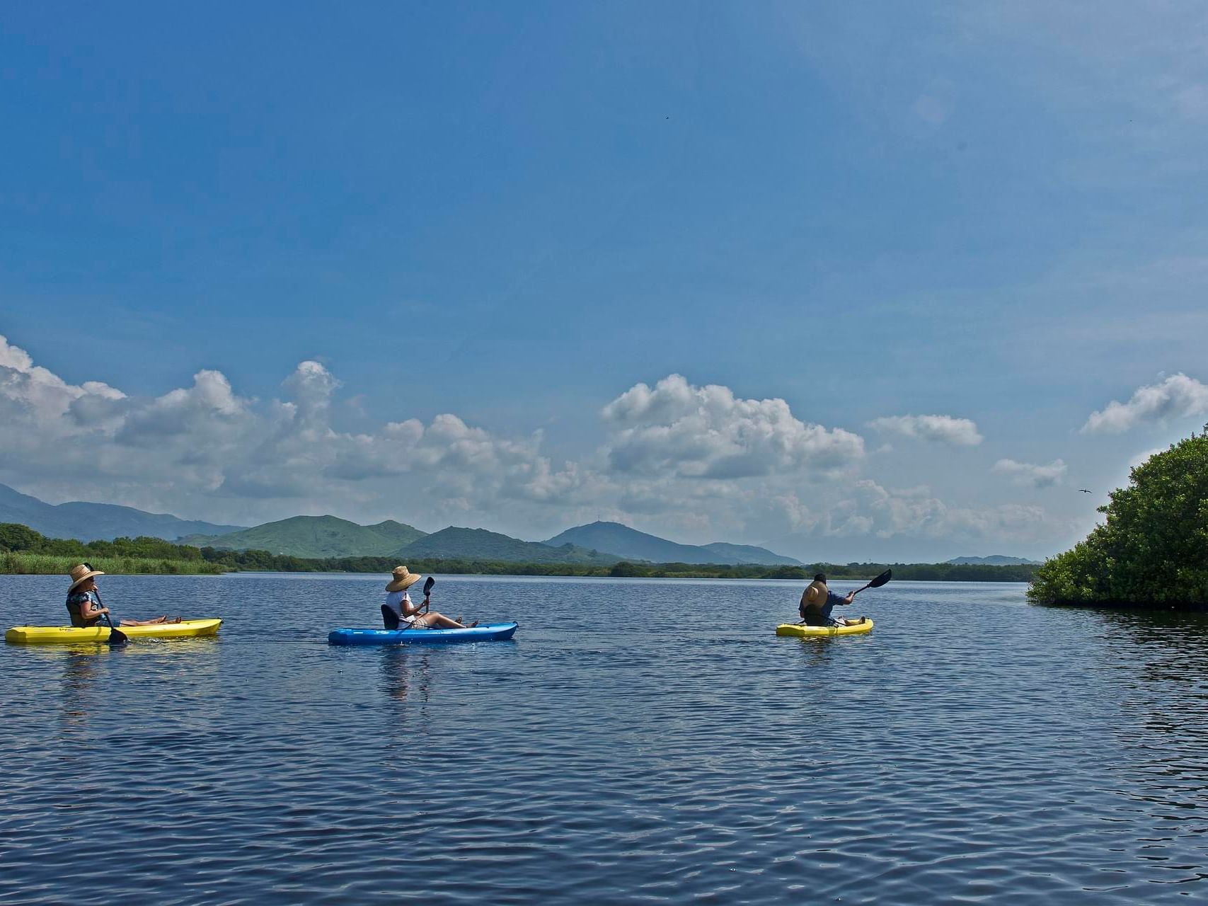 Three people kayaking on a river near Marea Beachfront Villas