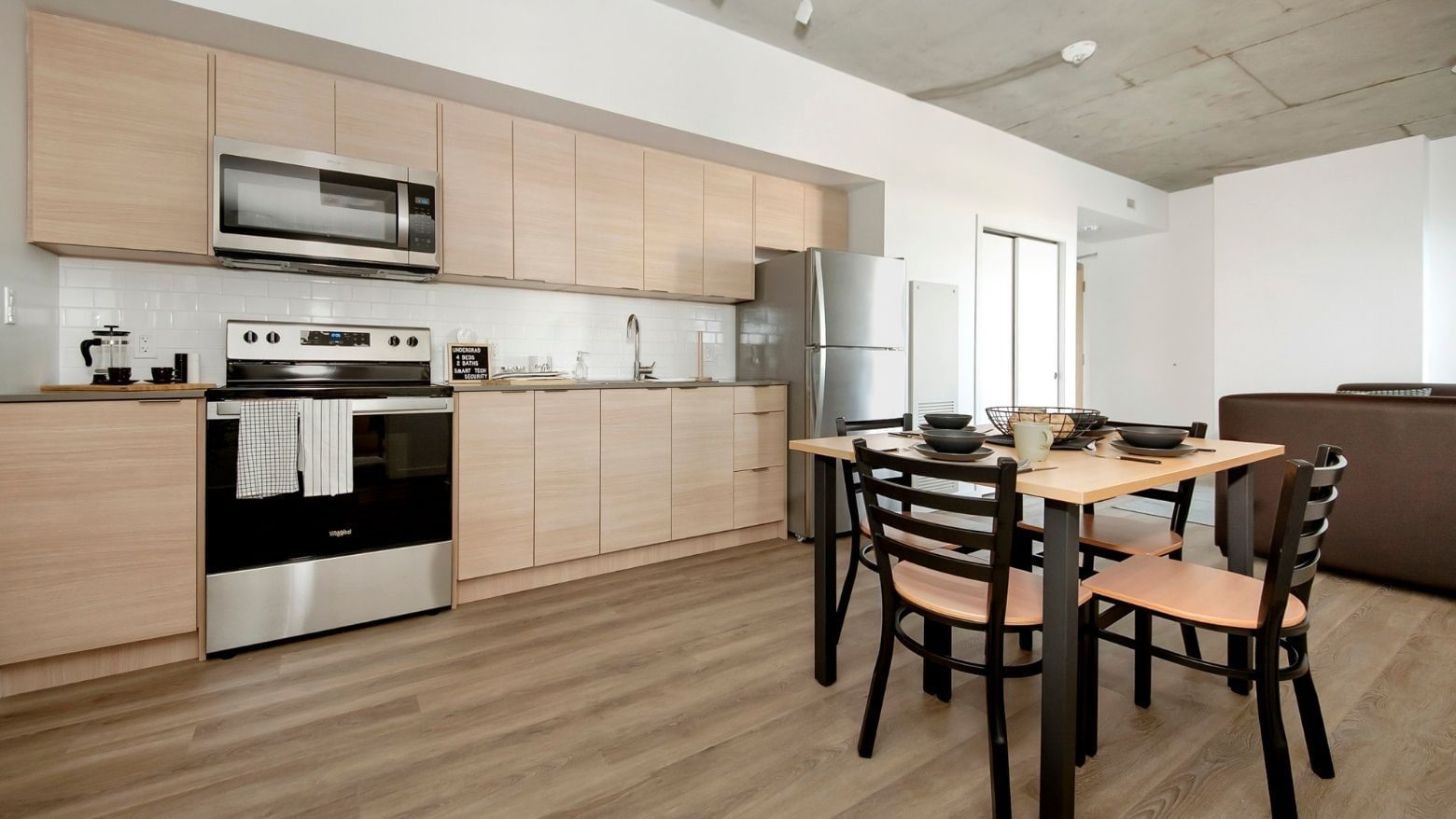 A sleek, full-sized kitchen with stainless steel appliances and a kitchen table with 4 chairs. 