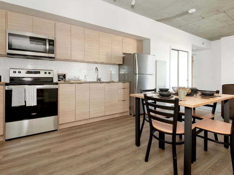 A modern and full sized kitchen with stainless steel appliances and a kitchen table with four seats.