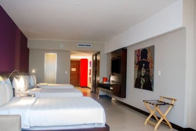 Beds with white linens beside a luggage rack and rock-themed art in Junior King with Balcony at Megapolis Hotel Panama