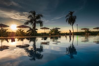 El área de la piscina con cabañas de piscina en Panoramic Grand durante la puesta de sol