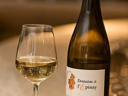 Verre de vin blanc et bouteille de vin à l'Hôtel Rivella.