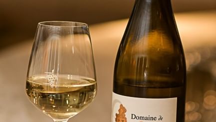 Verre de vin blanc et bouteille de vin à l'Hôtel Rivella.
