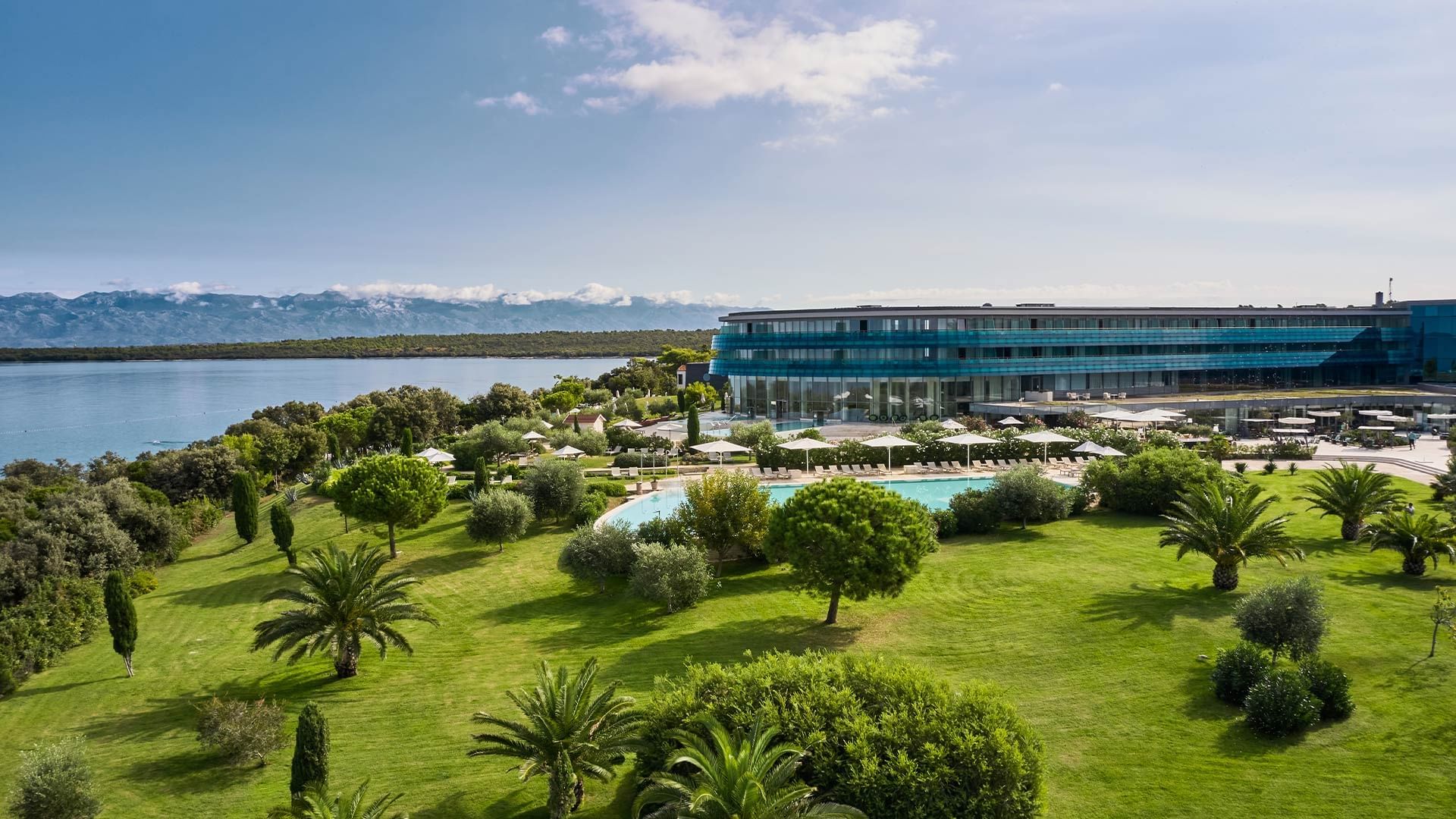 Aerial view of Falkensteiner Luxury Villas Punta Skala with pool and ocean surrounded by greenery