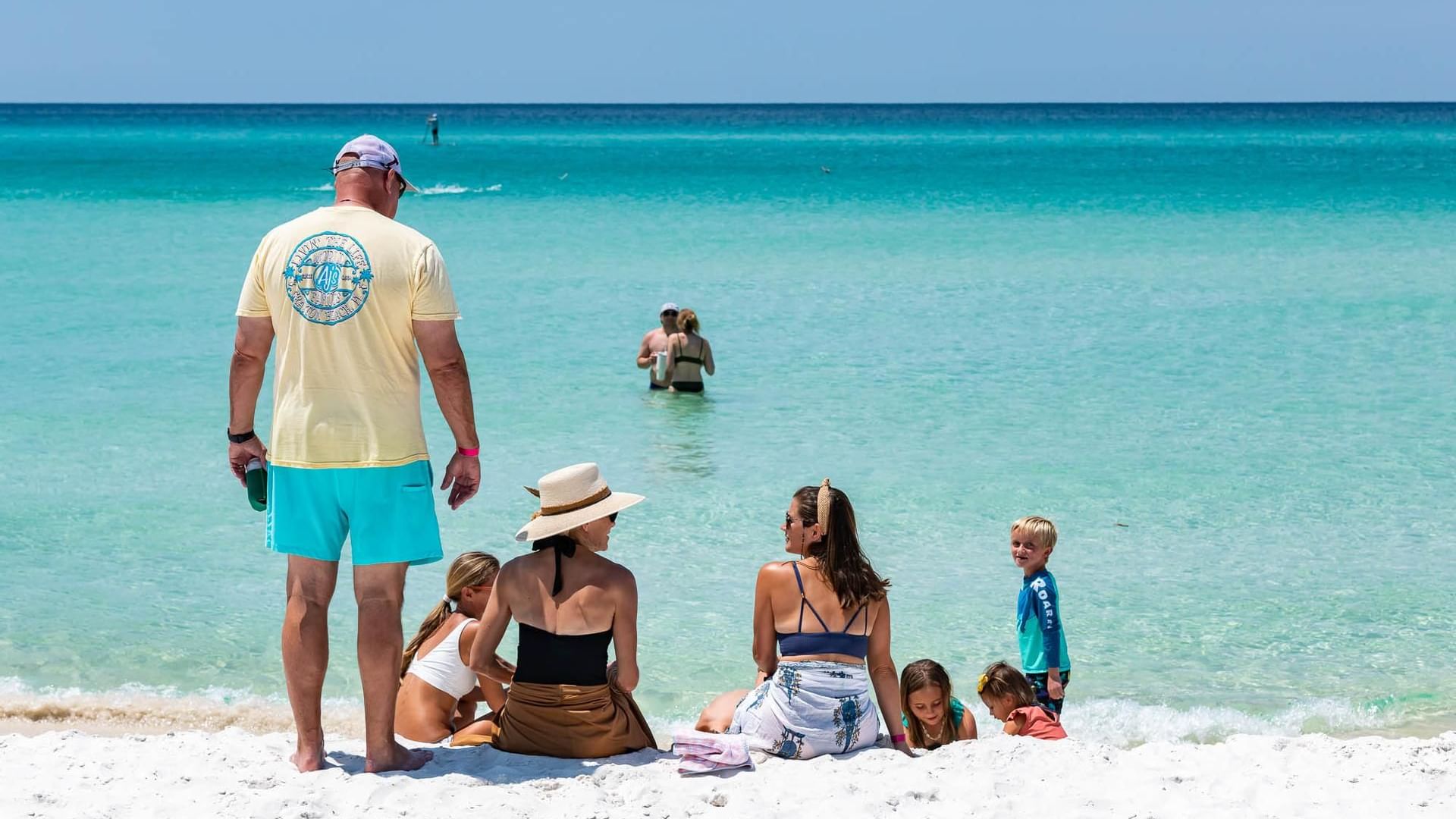 Families sit along the Watersound Beach Club private beach enjoying a sunny day