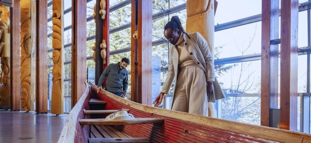 Guests exploring Indigenous art inside a Whistler cultural space with wooden carvings