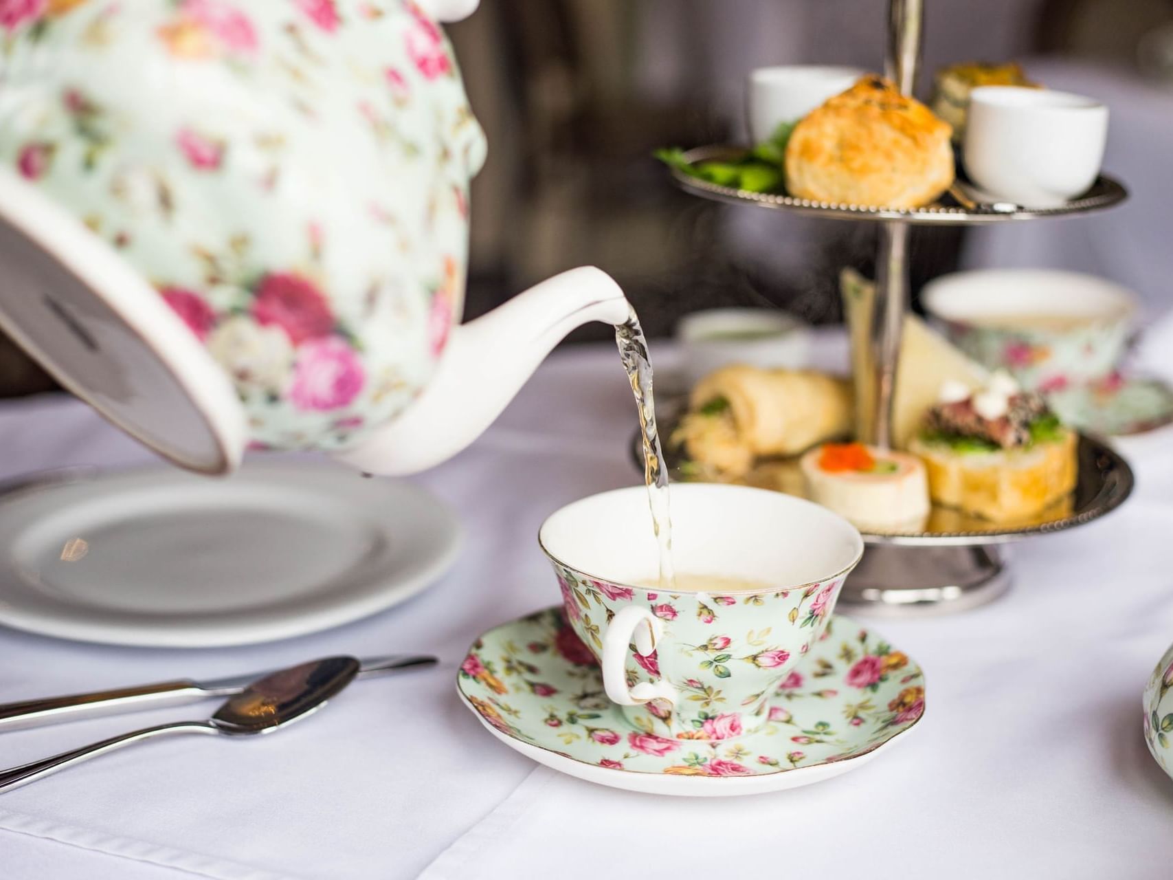 A teapot pouring tea into a cup in Pendray Tea House at Pendray Inn & Tea House