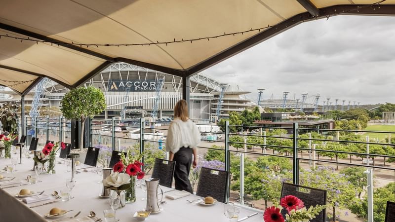 Beautifully set dining table with flowers on Freshwater Balcony, overlooking Accor Stadium at Novotel Sydney Olympic Park