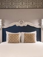 Bed with an ornate headboard by floating nightstands under brass lamps in Suite at Warwick San Francisco