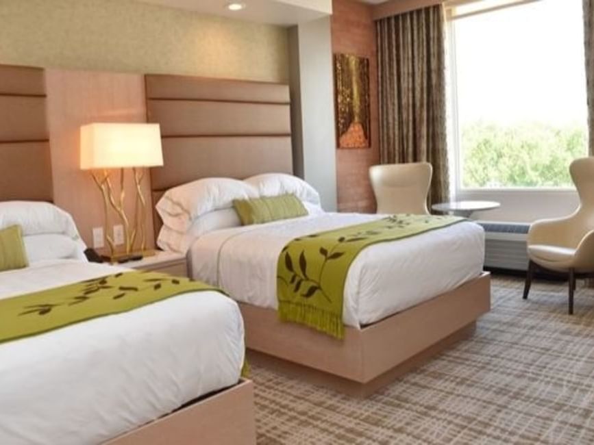 Two beds with a side table and a sitting area in Double Queen at The Fredonia Hotel