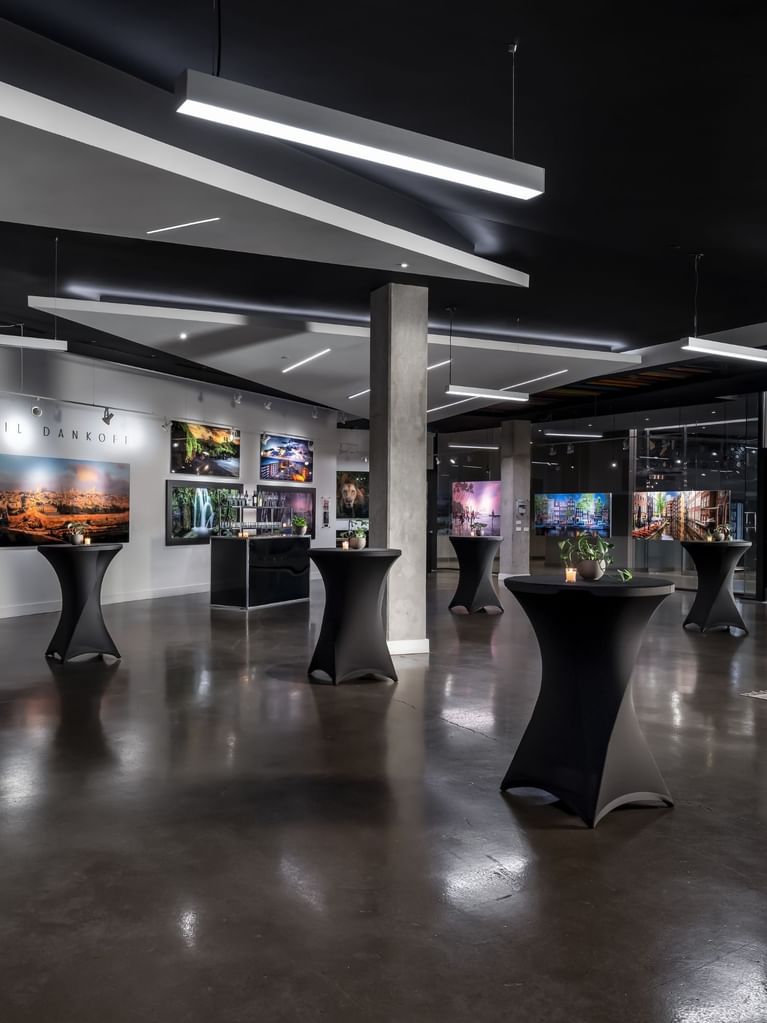 High-top cocktail tables spaced across a polished floor under modern lighting in a gallery venue at Hotel X Toronto