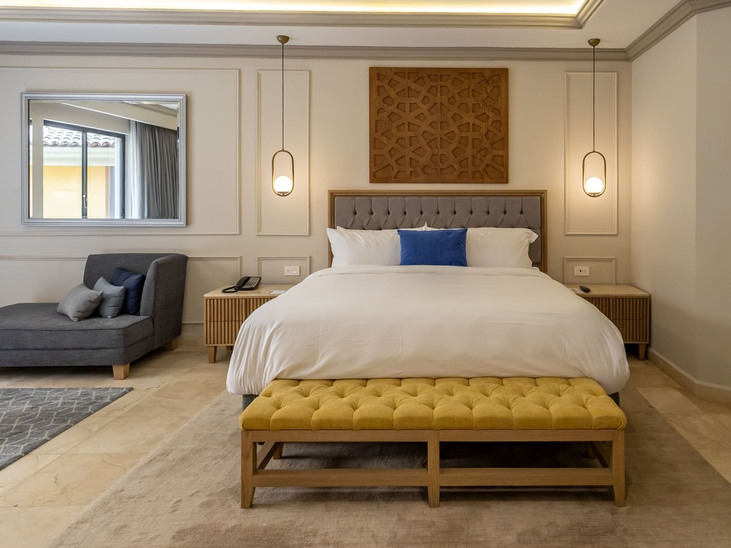 Spacious King Gran Class Gold Suite with tufted headboard, pendant lights, and gold bench at Quinta Real Monterrey.