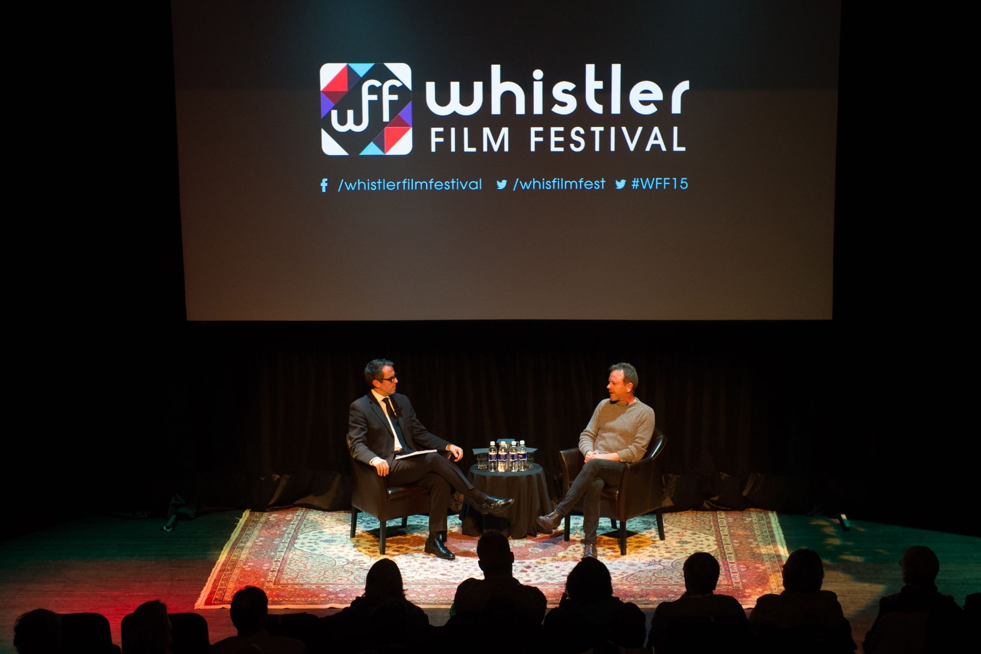Two men engaging in a conversation on a stage at the Whistler Film Festival near Blackcomb Springs Suites