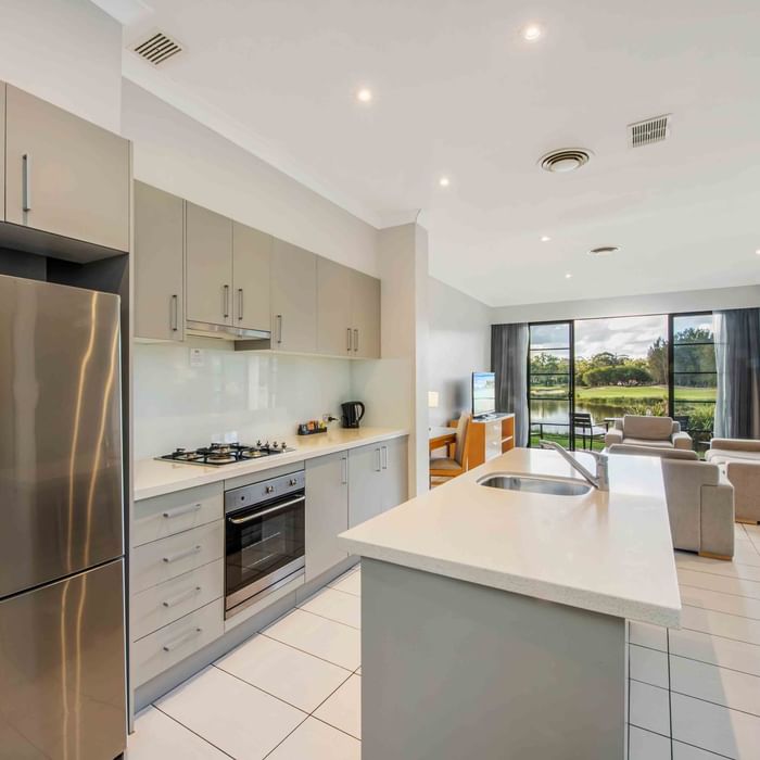 Three Bedroom Apartment kitchen with fridge and island, leading to a living room at Mercure Kooindah Waters