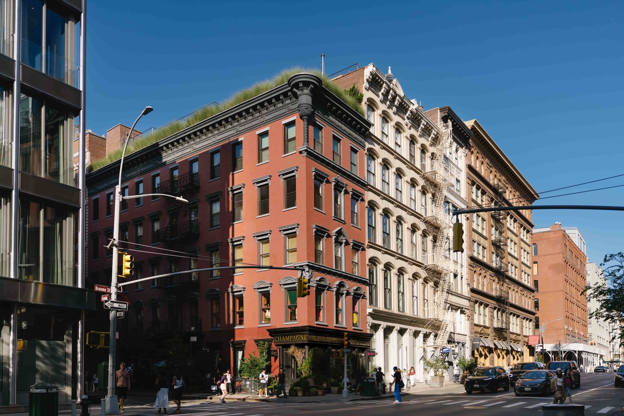 A corner view of a row of buildings in New York City, with a green roof on top of the leftmost building.