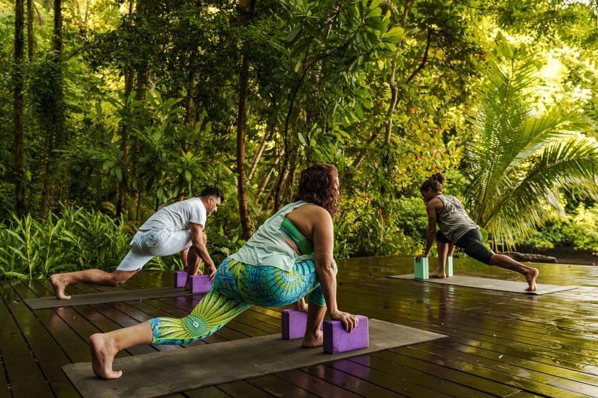 Three people doing yoga on Alma Yoga Dock at Playa Cativo Lodge