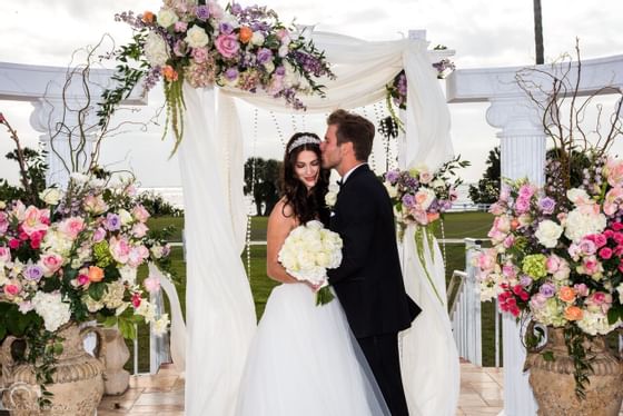 Newlyweds kissing during outdoor wedding.