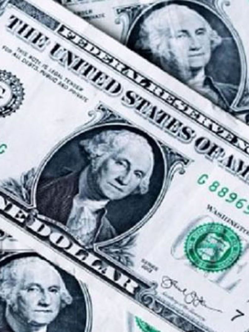 Collection of one-dollar bills featuring George Washington placed in a pile at Warwick Seattle