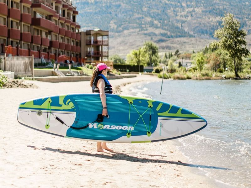 women about to enter Osoyoos Lake with a paddleboard