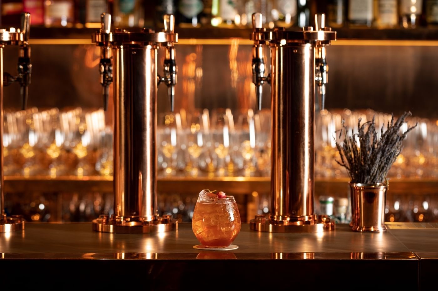 Handcrafted cocktail on the bar, set in front of gleaming copper beer taps at The Londoner hotel's pub