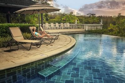 woman laying out next to pool in tropical setting