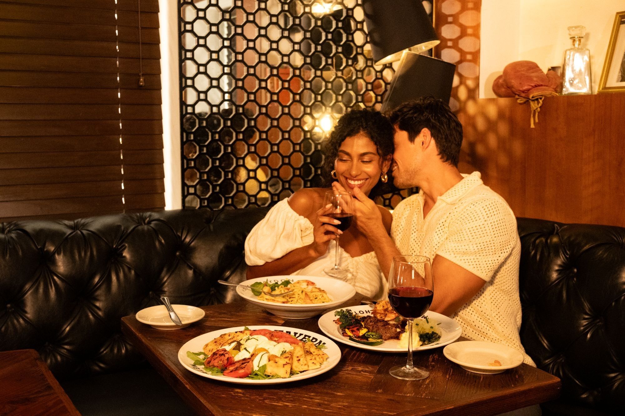 A couple is sitting at a table in a dining area, enjoying their meal and each other's company.