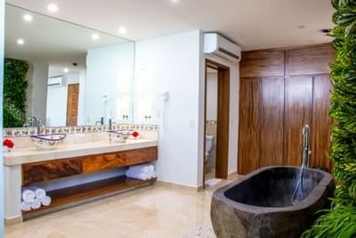 Modern bathroom with stone bathtub, wooden vanity, and living wall at Playa Los Arcos Puerto Vallarta 2023